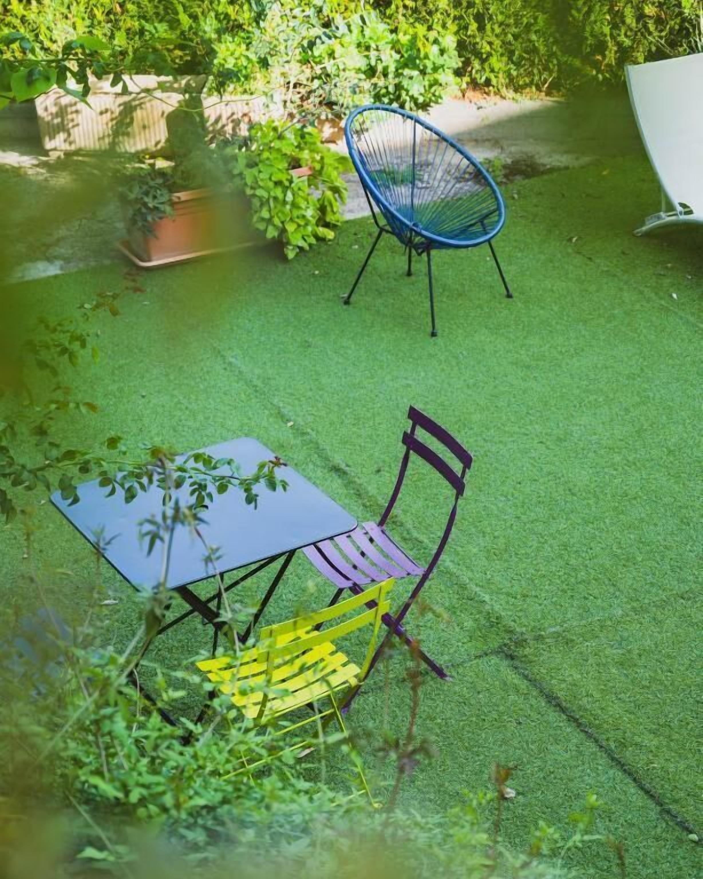 Un patio con una mesa y sillas, rodeado de follaje.