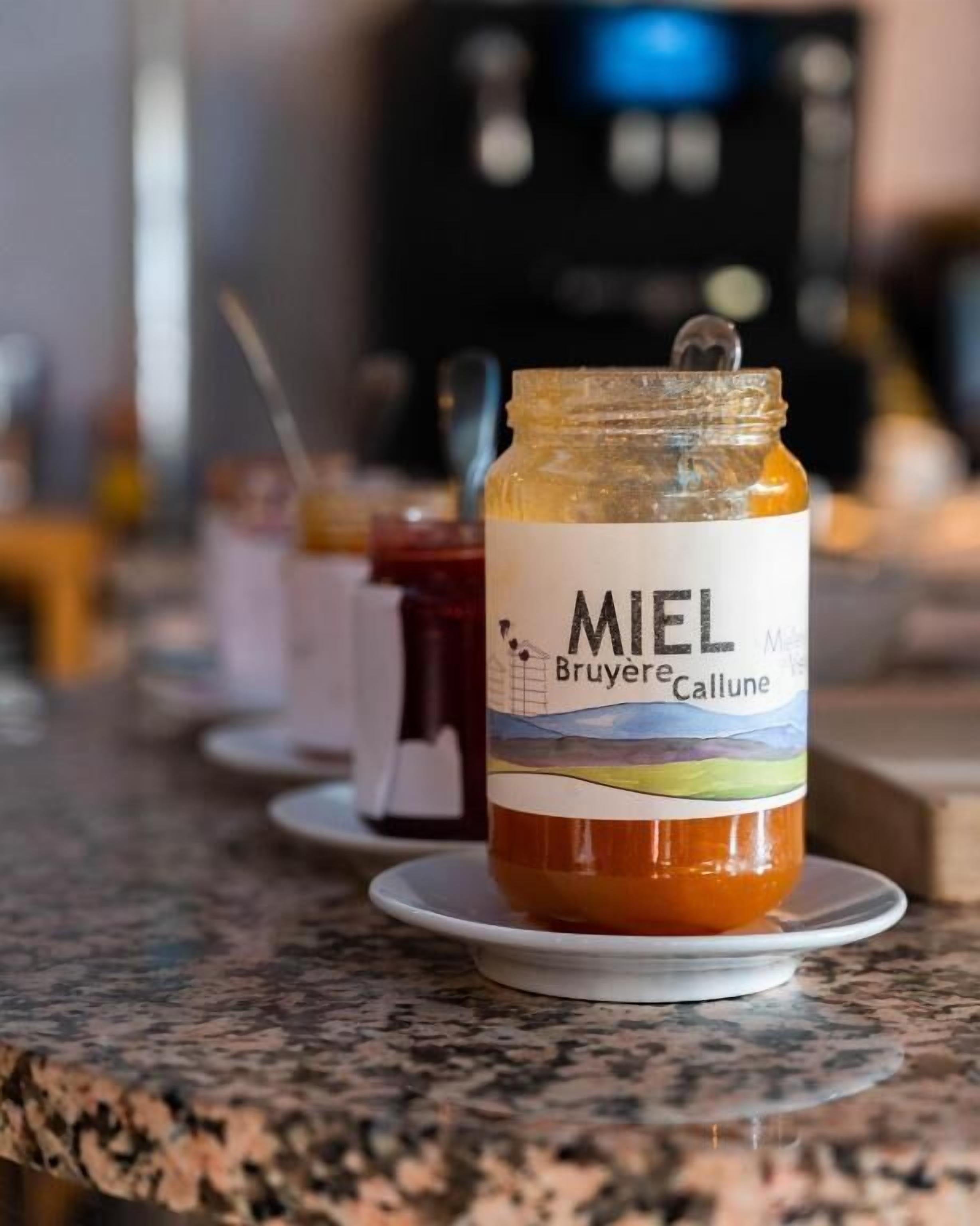 A jar of Miel Bruyere Callune on a countertop with other jars in the background.