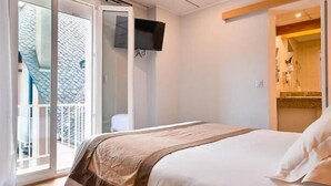 Ein Schlafzimmer mit einem Bett, einem Fernseher, einer Schiebetür und einem durch eine offene Tür einsehbaren Badezimmer.