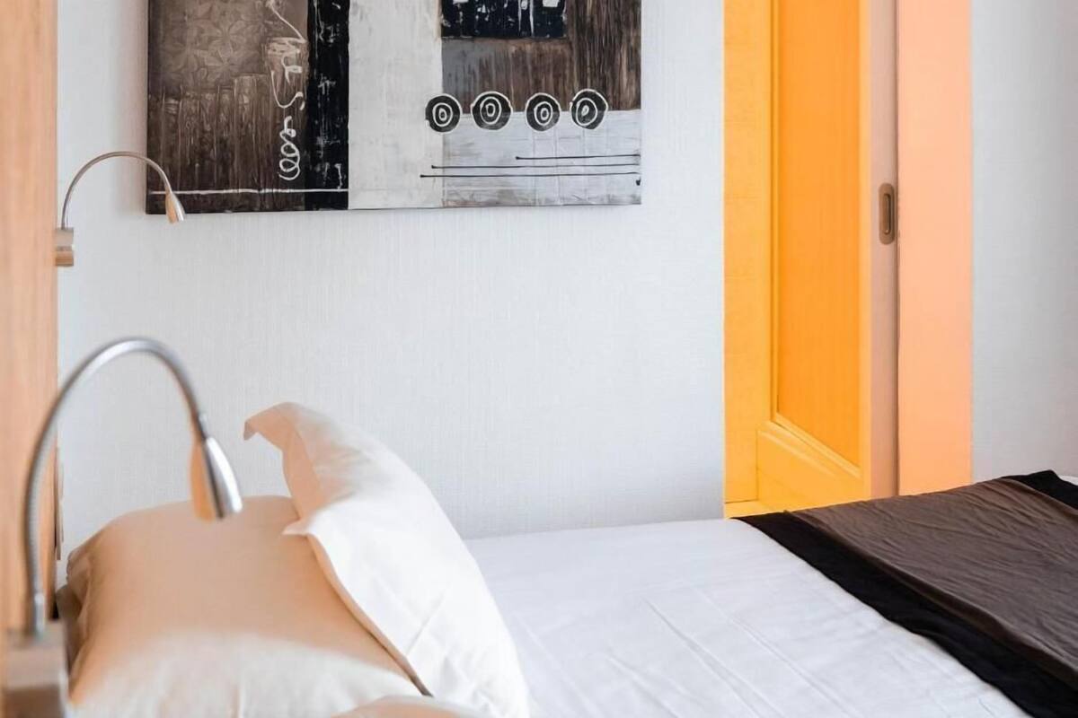 A bed with white bedding, a metal faucet, and a painting on the wall.