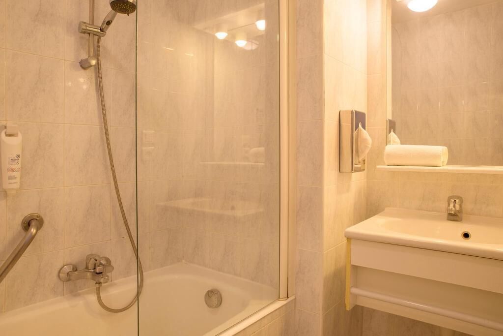 A modern bathroom with a glass-enclosed shower, a white sink, and a mirror.