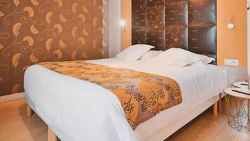 Habitación de hotel moderna con una cama grande, piso de madera, pared estampada y un cabecero decorativo.