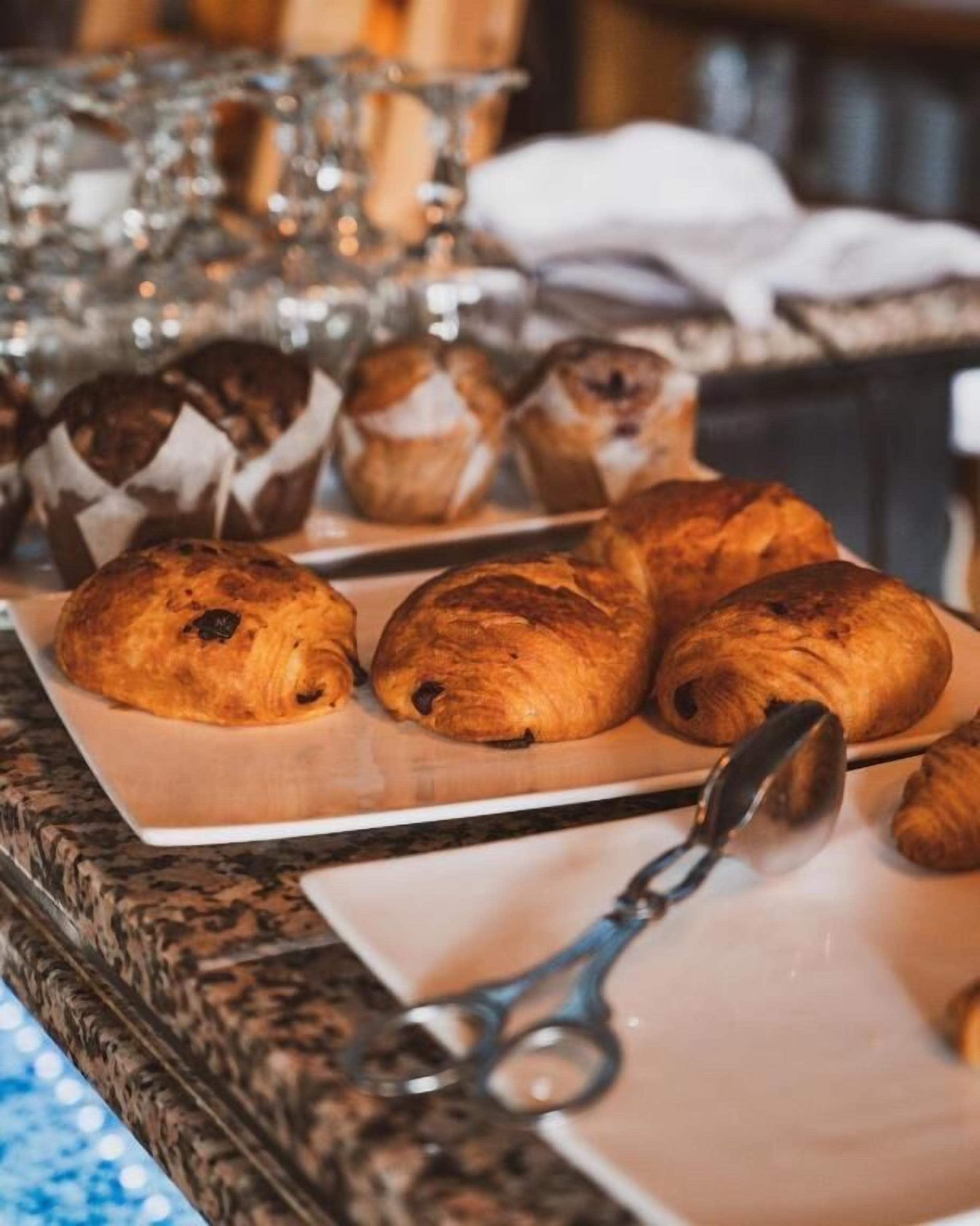 A tray of baked goods, including croissants and muffins, on a table.