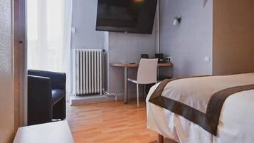 Een hotelkamer met een bed, een bureau, een stoel, een televisie en een radiator.