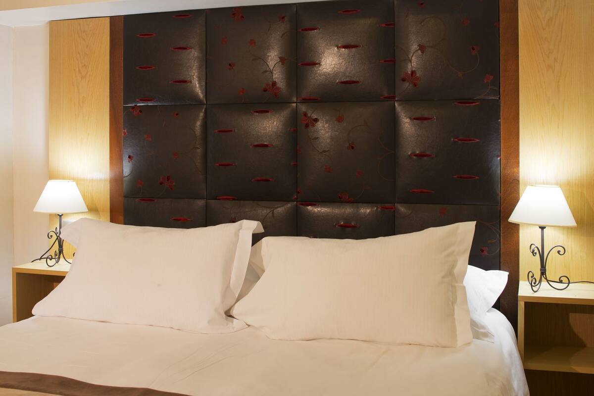 A bed with a headboard, two bedside tables, and lamps.
