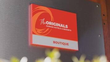 Letrero en una pared que dice 'The Originals Human Hotels & Resorts Boutique'.