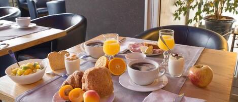 A breakfast setting with a table, plates of food, and a cup of coffee.