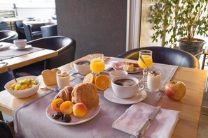 Un desayuno con una mesa, platos de comida y una taza de café.