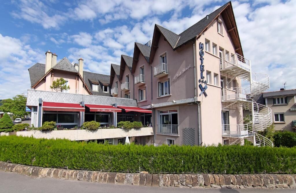 A hotel with multiple balconies, a covered outdoor seating area, and a spiral staircase.
