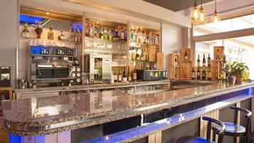 Una zona de bar con encimera de granito, taburetes, una estantería para vinos y una cafetera.