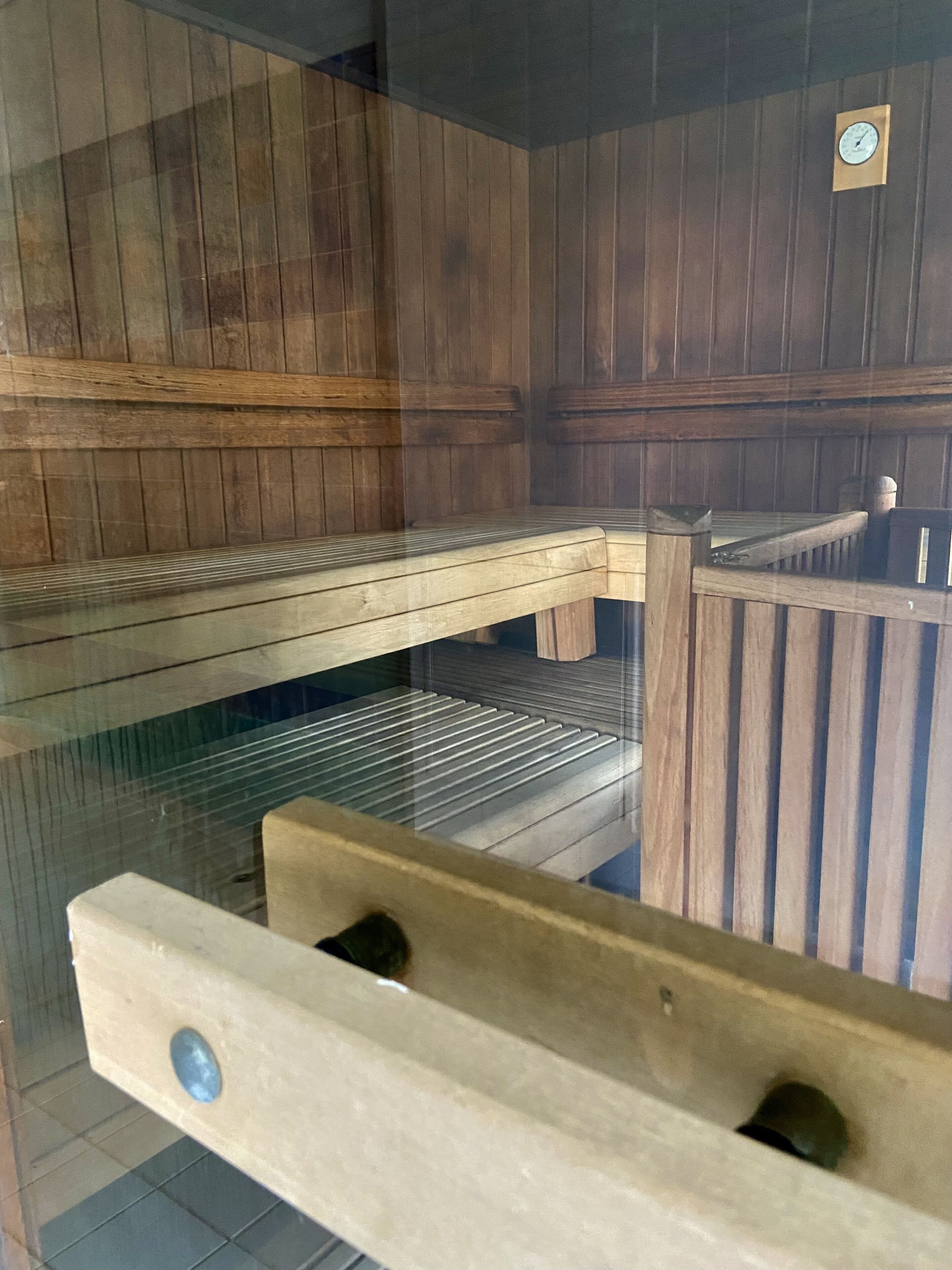 A sauna with wooden benches and a glass enclosure.