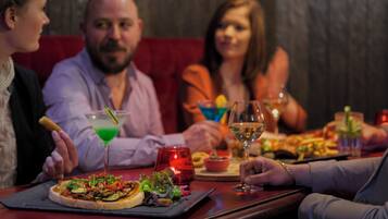 Un grupo de personas cenando en un restaurante con diversos platos y bebidas sobre la mesa.