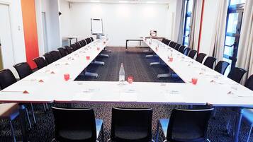 Un salón de conferencias con una larga mesa, sillas, tarjetas de identificación y una pantalla para proyector.