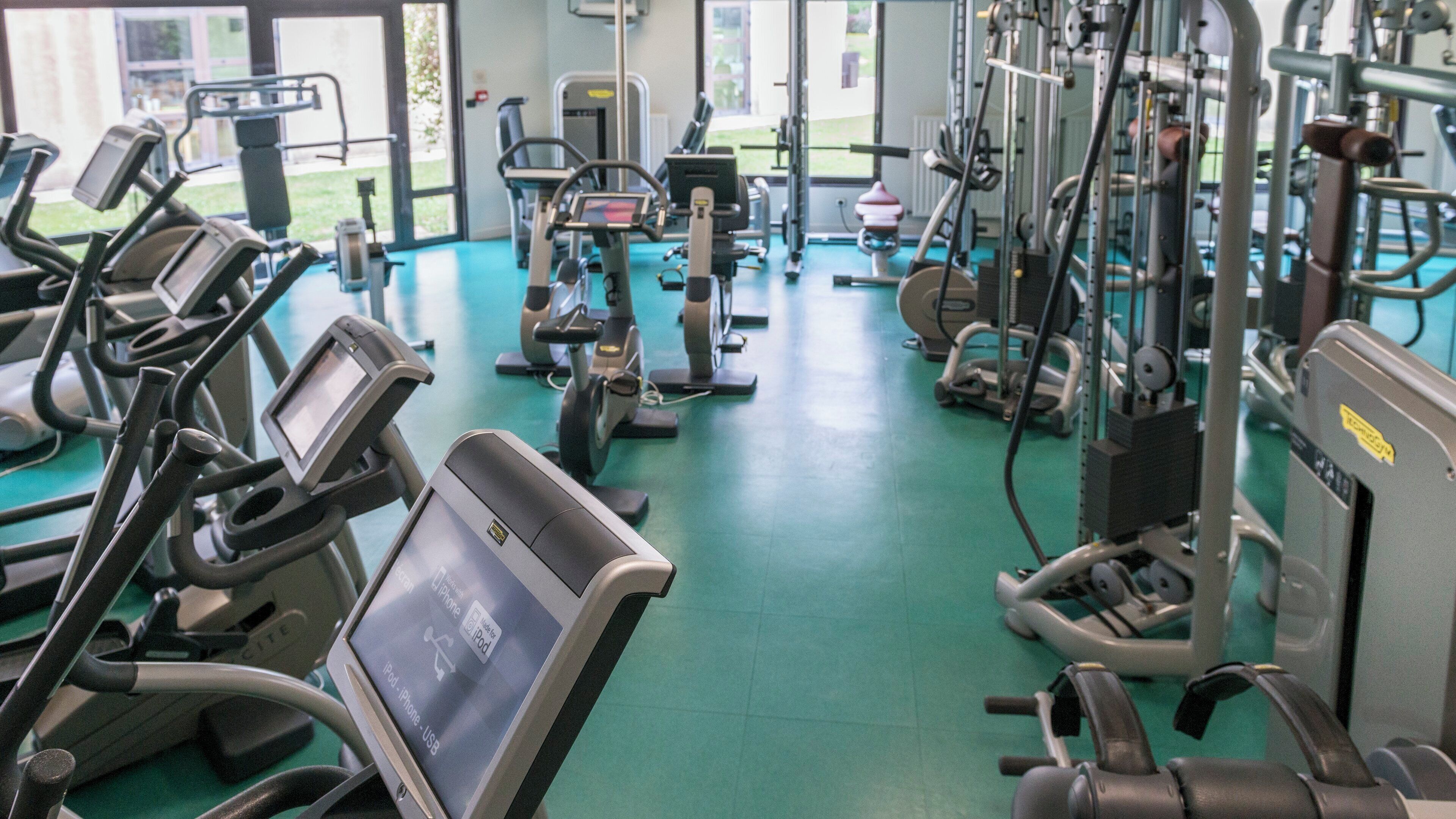 Un gimnasio con diverso equipo de ejercicio, incluyendo cintas de correr y máquinas de pesas.