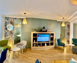 A modern living room with a television, comfortable seating, and decorative wall art.