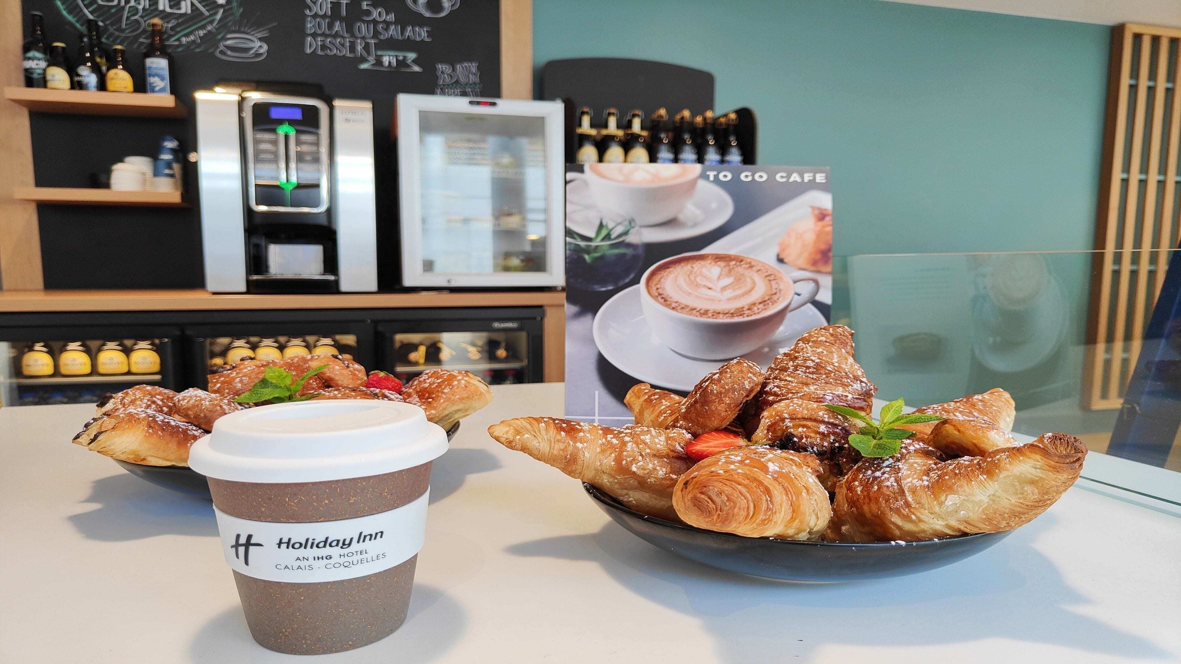A breakfast setting with croissants, a coffee cup, and a menu board in a cafe.