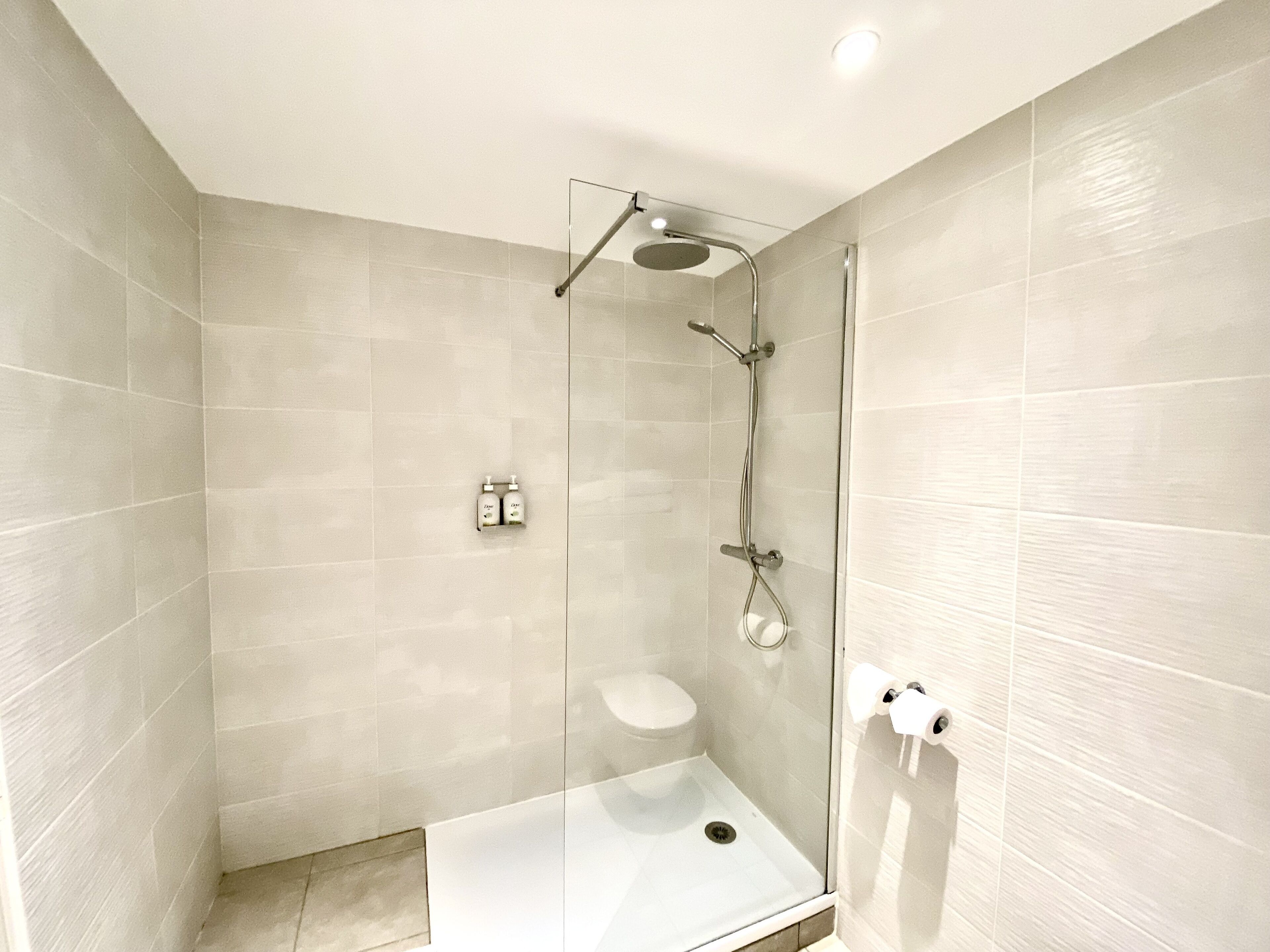 Une salle de bain moderne dotée d’une douche à parois de verre, de toilettes et d’un lavabo.