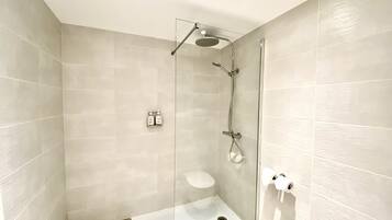 Un baño moderno con ducha vidriada, inodoro y lavamanos.