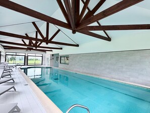 An indoor swimming pool with clear glass walls, wooden beams, and a tiled floor. - Holiday Inn Calais-Coquelles by IHG (Coquelles)
