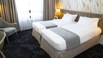 Une chambre d’hôtel avec deux lits, une chaise, une lampe et une grande fenêtre avec des rideaux.