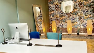 A reception desk with a laptop, a blue chair, and a decorative wall with a mirror and cacti.