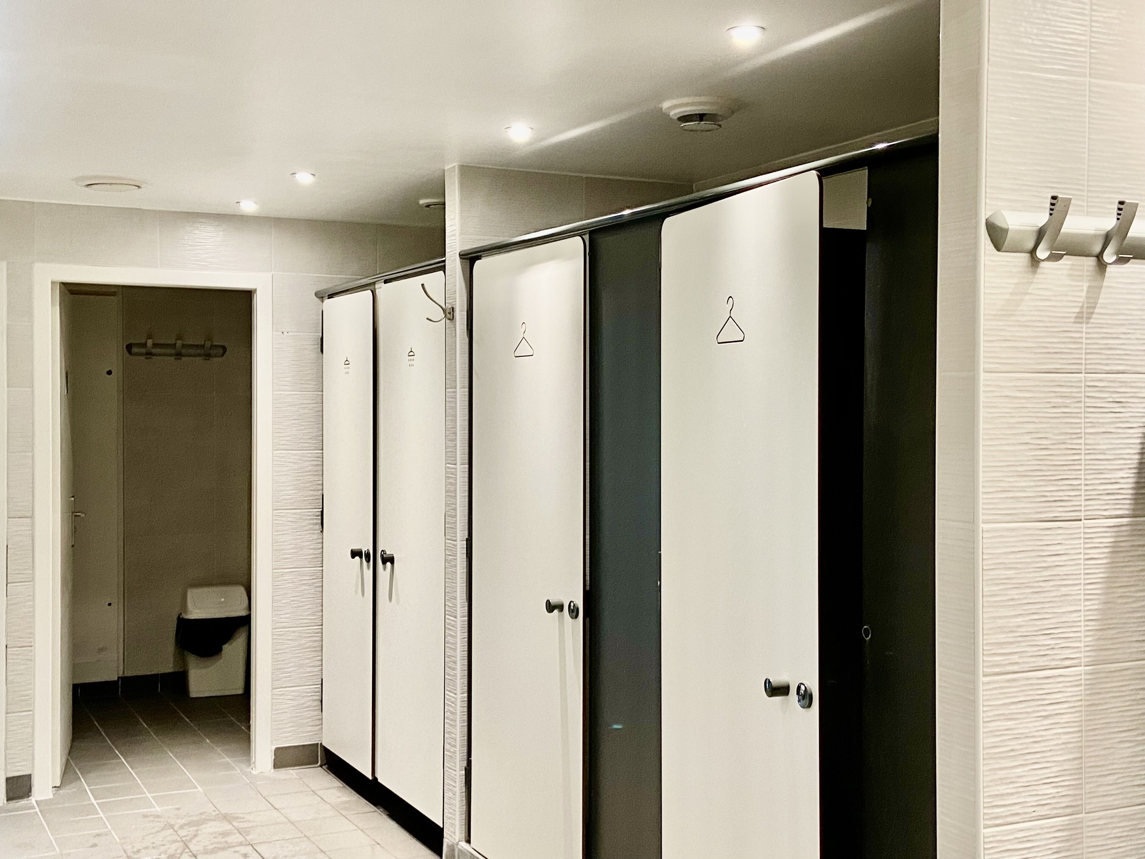 Eine Reihe von Badezimmern mit eigenem Bad, jeweils mit Dusche, Toilette und Handtuchhalter.