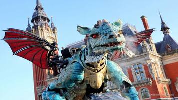A dragon statue with wings, set against a historic building with multiple spires.