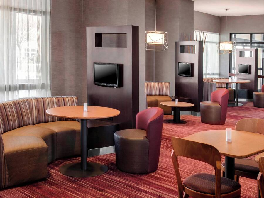A modern hotel lobby with a sectional sofa, round tables, and comfortable seating.
