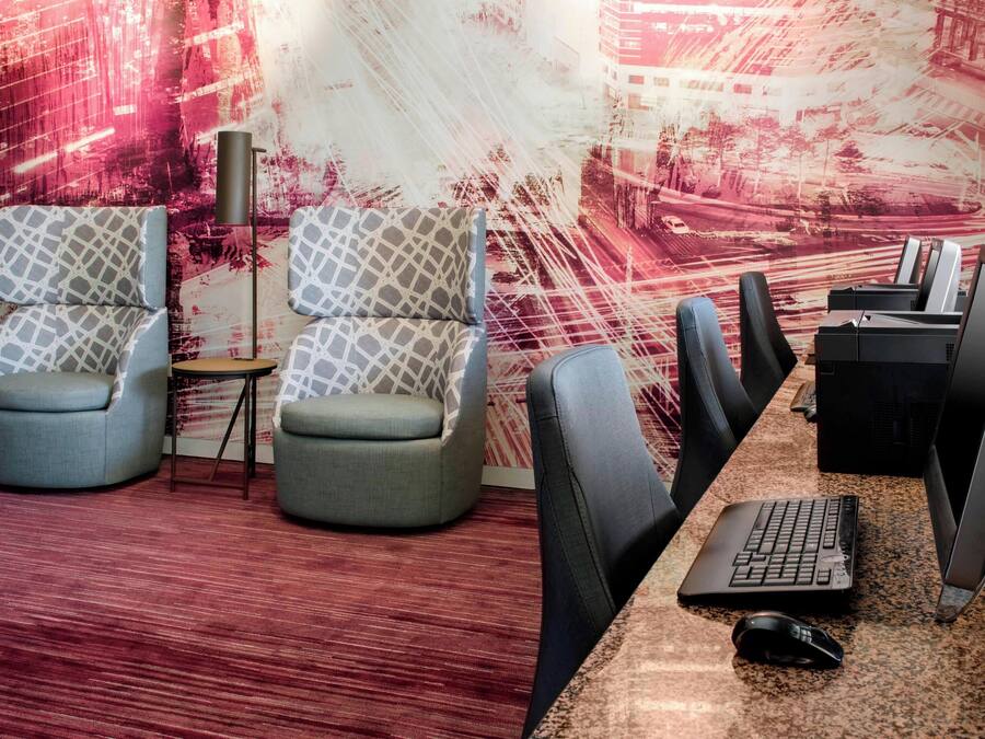 Um espaço de escritório moderno com duas cadeiras estampadas, uma mesa com um laptop e um monitor de computador.