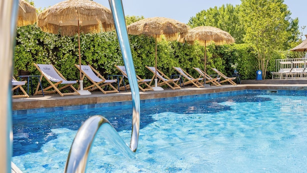A poolside area with lounge chairs and thatched umbrellas. - Hôtel Europe (La Grande-Motte)