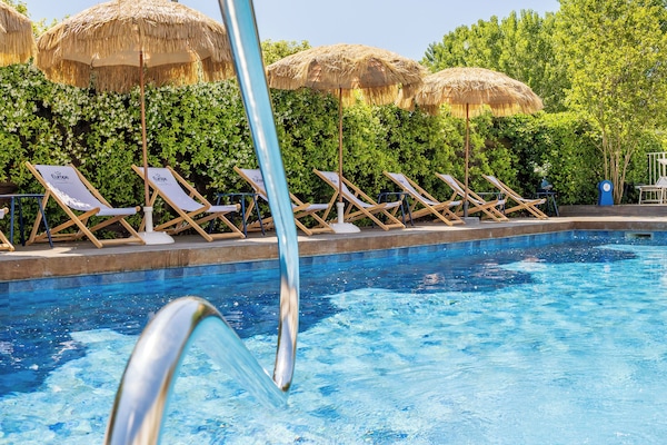 En säsongsöppen utomhuspool, parasoller och solstolar