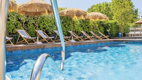 Una piscina al aire libre de temporada, sombrillas