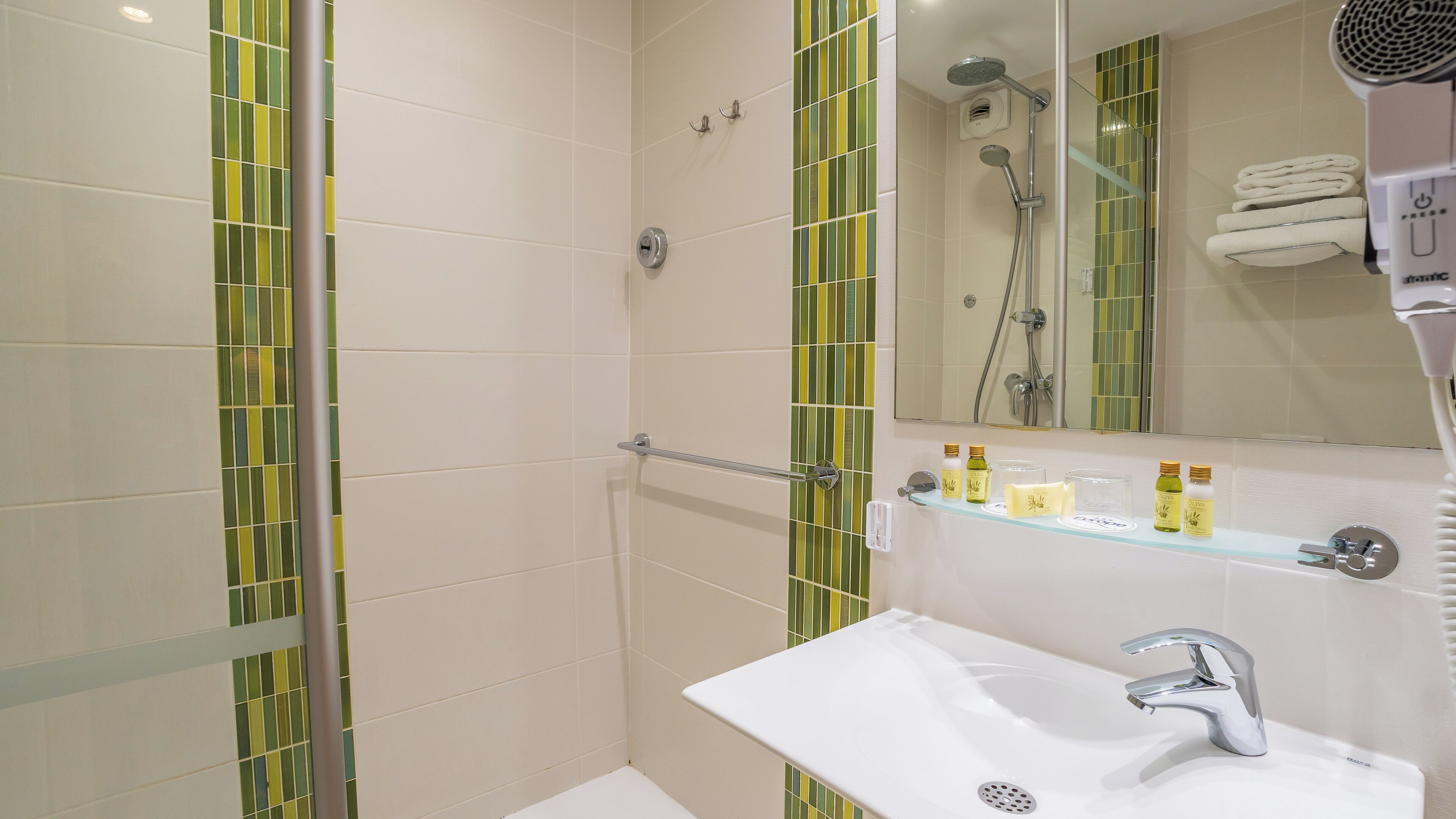 A modern bathroom with a glass shower enclosure, a white sink with a chrome faucet, and a mirror above the sink.