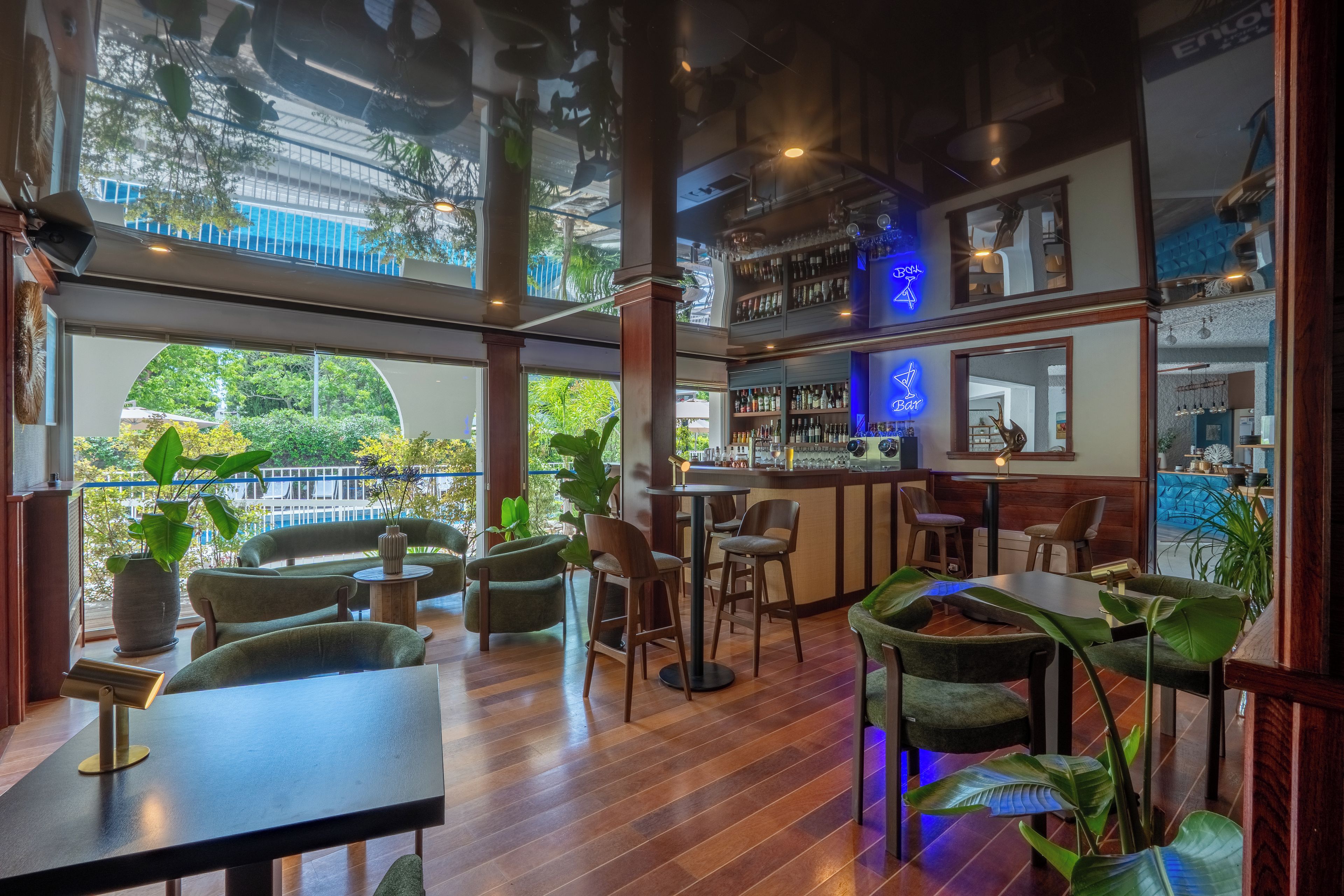 Un restaurant doté d’un bar, de tables et offrant une vue sur l’extérieur.