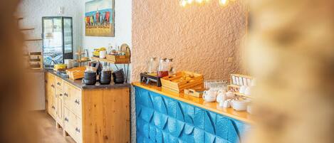 Una barra de desayuno con diversos alimentos y bebidas, un cuadro con sillas de playa y una pared con textura.