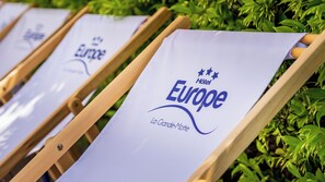 Una hilera de sillones de descanso con cojines blancos, cada uno con el logotipo de 'Europe Hotel' y el texto 'La Grande-Motte'.