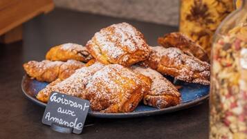 Een bord gebakjes bestrooid met poedersuiker, met een bordje dat aangeeft dat ze met amandel zijn gemaakt.