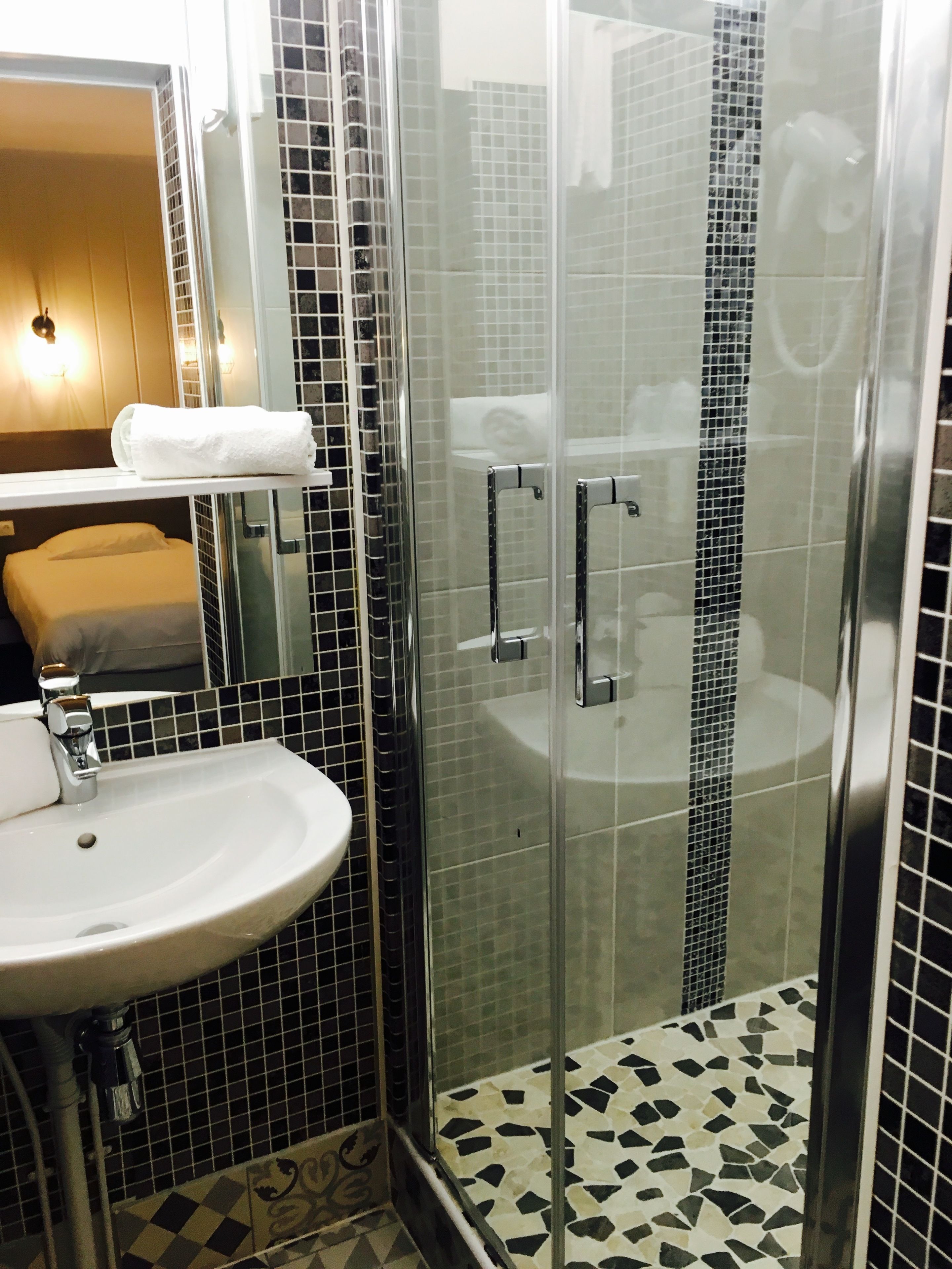 A bathroom with a glass-enclosed shower, a white sink, and a mirror.