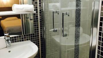 Une salle de bain avec une douche à parois de verre, un lavabo blanc et un miroir.