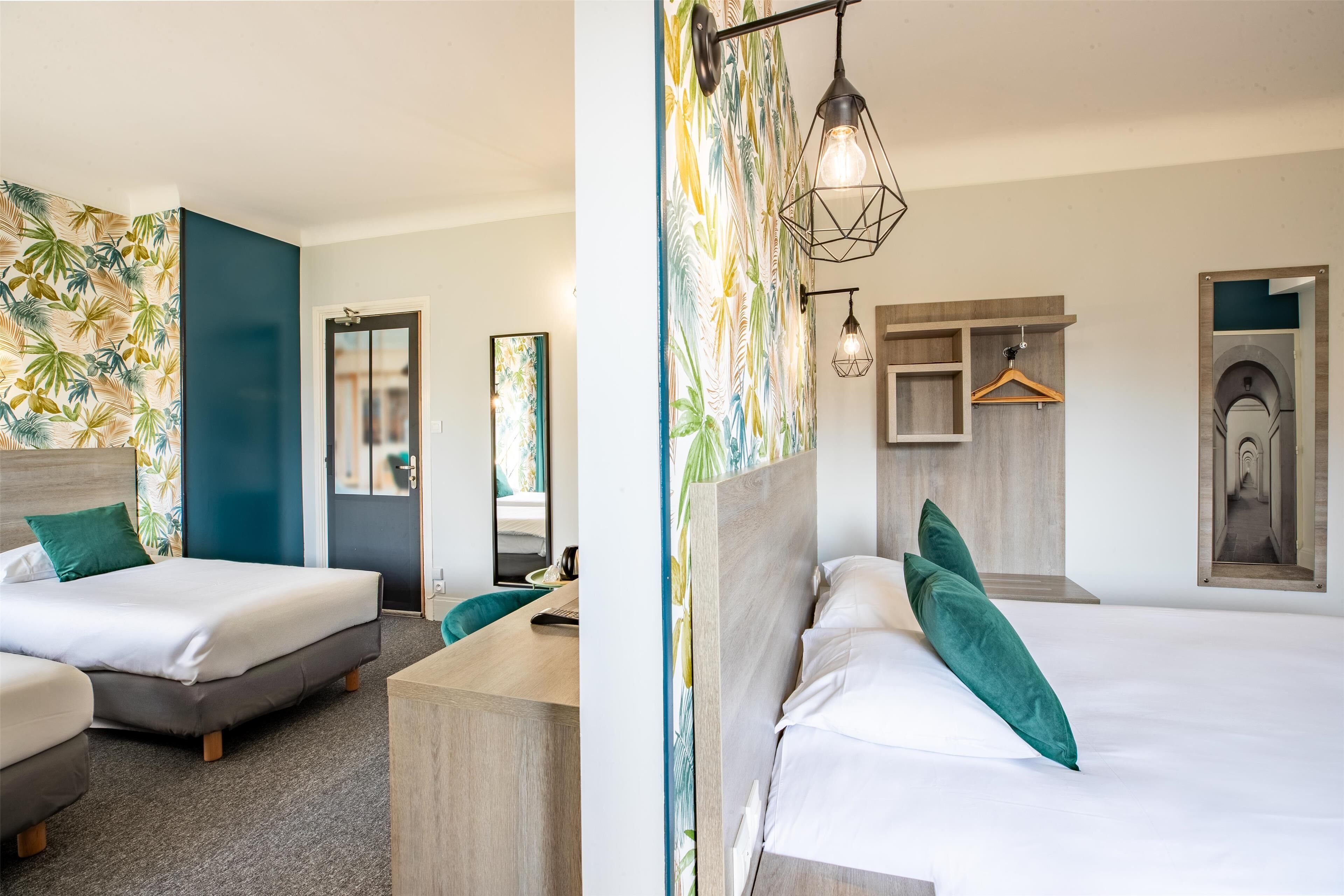 Ein Hotelzimmer mit zwei Betten, einem Schreibtisch und einem Spiegel.
