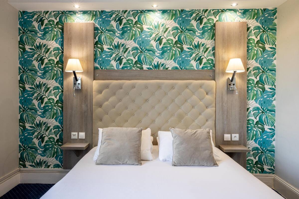 A bedroom with a tufted headboard, two bedside lamps, and a bed with pillows.