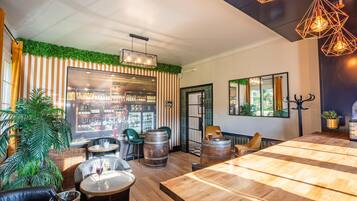 Un espace bar accueillant, avec des tables en bois, des sièges en cuir et une grande fenêtre donnant sur le bar.