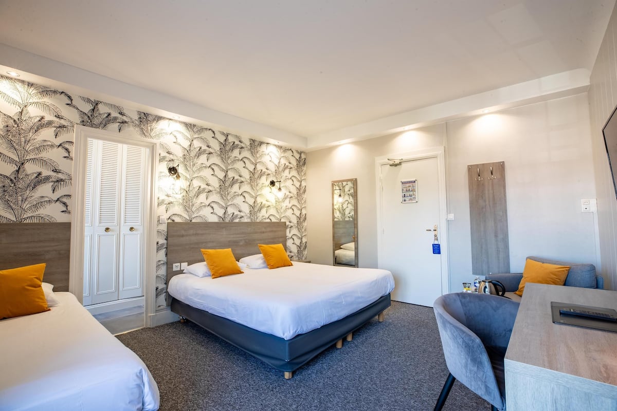 A hotel room with a large bed, two bedside tables, a desk, and a chair.