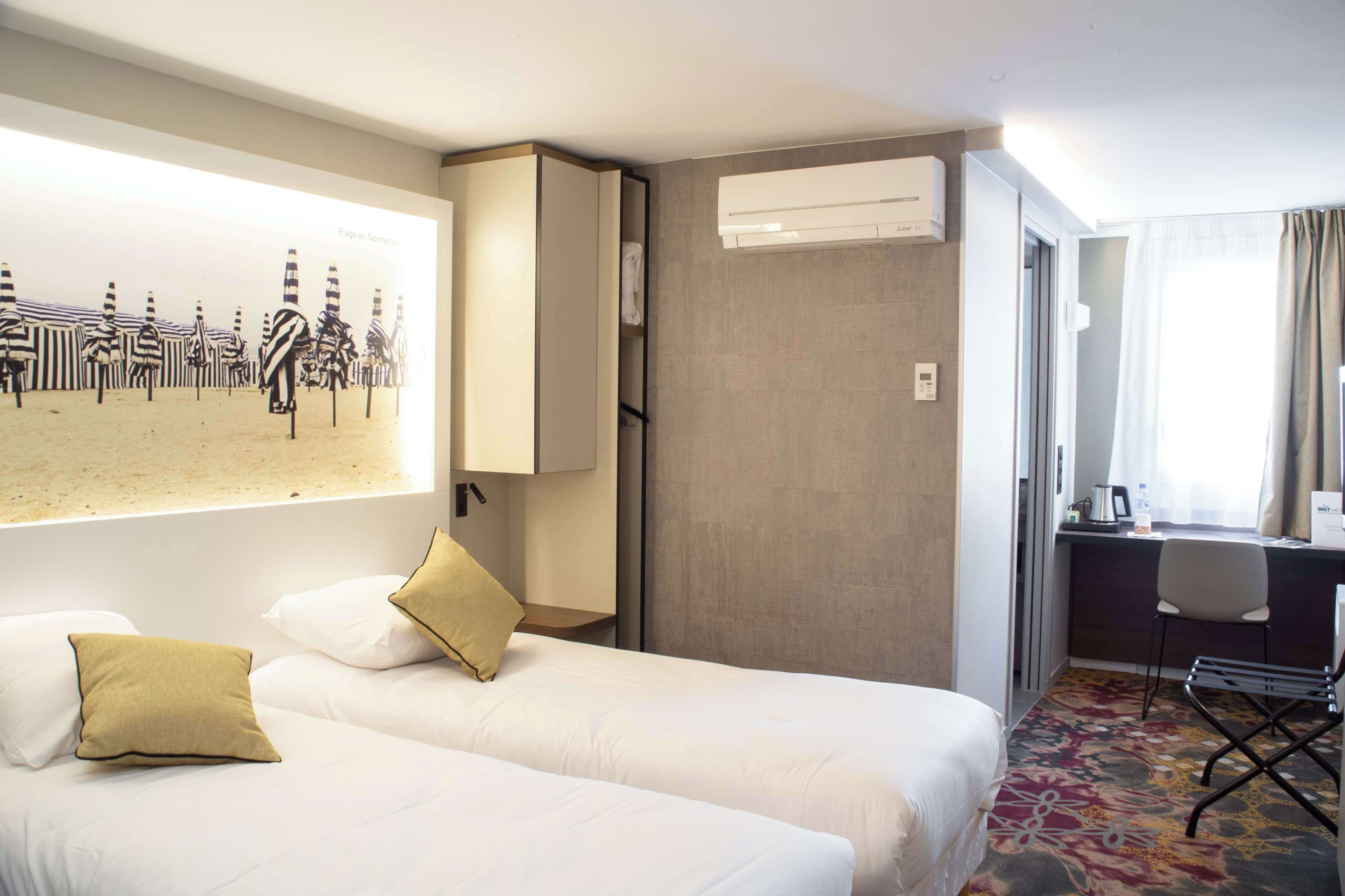 Een hotelkamer met twee bedden, een bureau, een stoel en een groot raam.