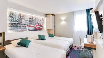 A hotel room with two beds, a desk, a TV, and a large window with curtains.
