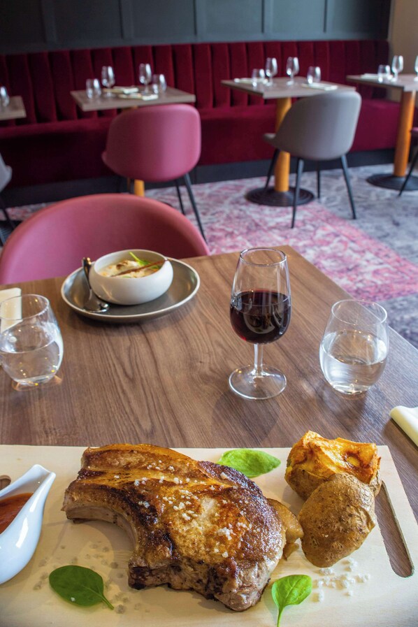 A dining table with a plate of food, a glass of red wine, and a water glass.