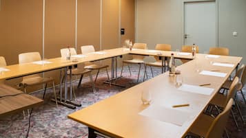 A conference room with long tables, chairs, and a carpeted floor.