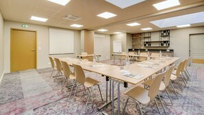 A conference room with a long table, chairs, a whiteboard, and a brick accent wall.
