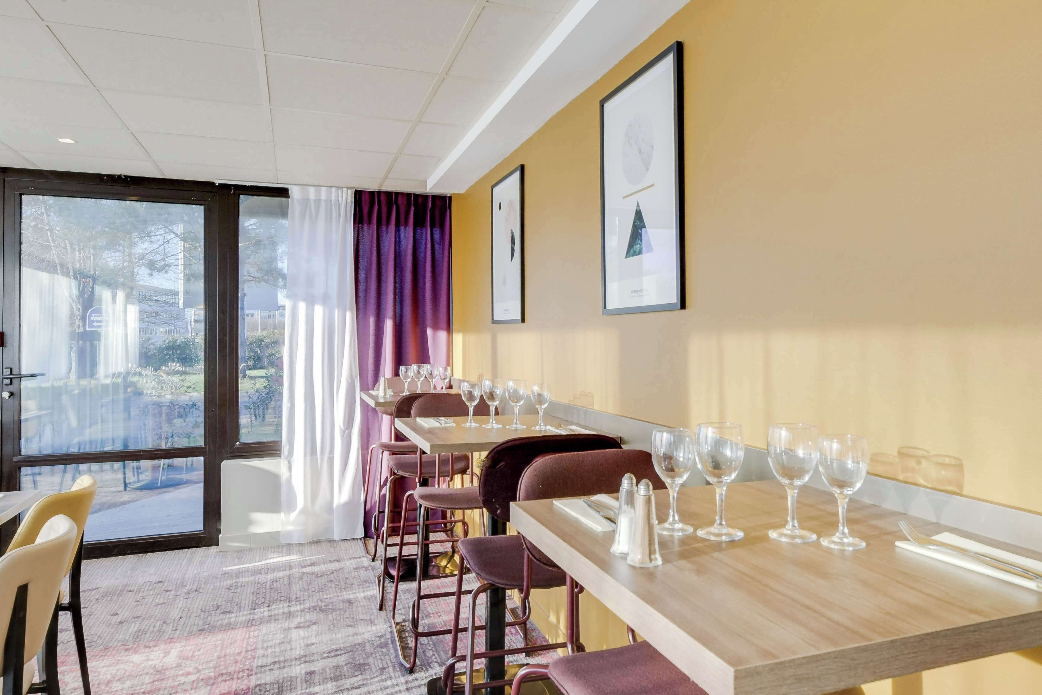 Une salle à manger d’hôtel avec plusieurs tables, des chaises et des tableaux encadrés accrochés au mur.