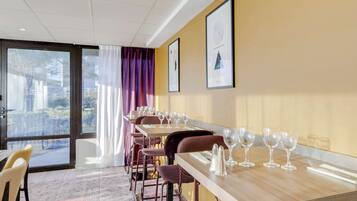 Une salle à manger d’hôtel avec plusieurs tables, des chaises et des tableaux encadrés accrochés au mur.